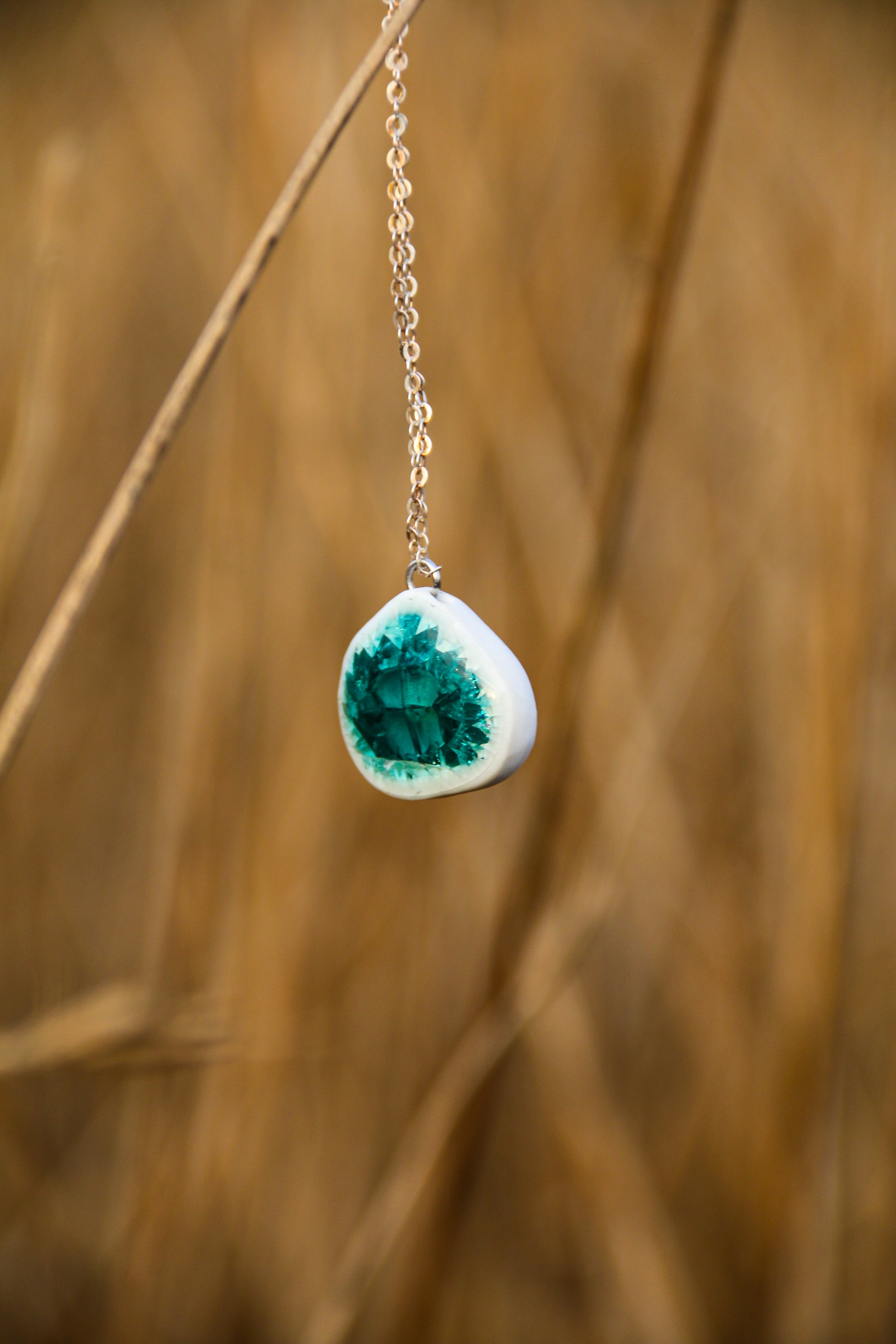 Necklace with a green geode pendant against a blurred natural background